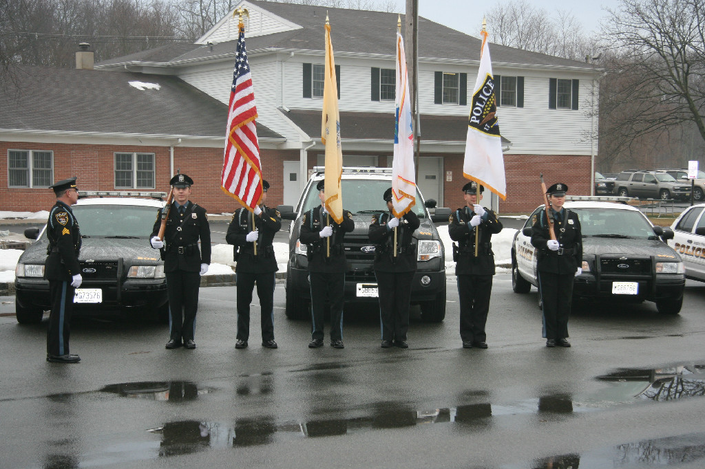 Honor Guard posing with flags in front of a line of cruisers. 